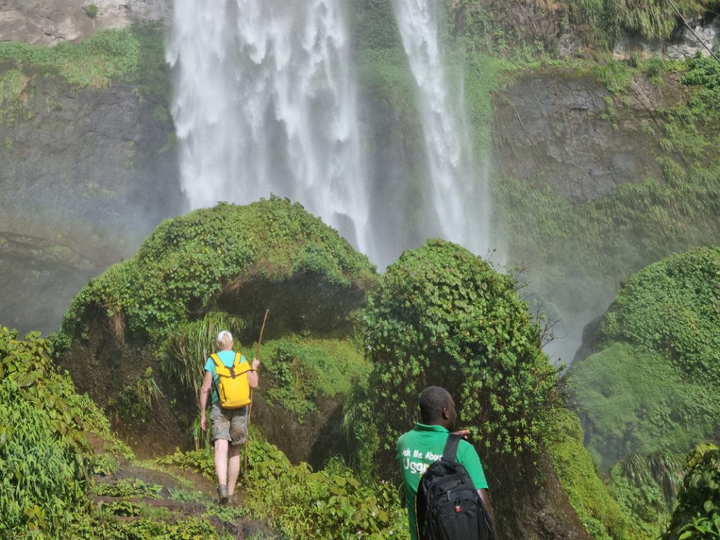 Tourist of Elgon Safaris Uganda walking at the Sipi Falls during the 4 day Uganda Hike Tour